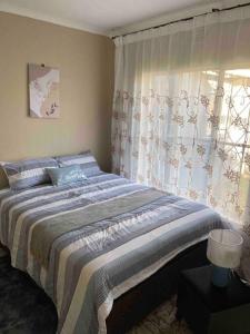 约翰内斯堡Home in Suideoord, Jhb south的一间卧室设有一张大床和一个窗户。
