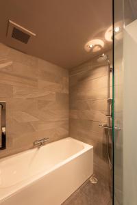 金泽NODE SAIGAWA的带浴缸和玻璃淋浴间的浴室。