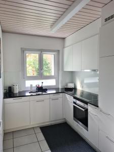 苏黎世2 BR - Kingsize Bett - Garten - Parken - Küche的厨房配有白色橱柜和黑色台面