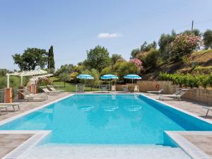 渥尔特拉Lavish Holiday Home in Volterra with Pool的一个带椅子和遮阳伞的大型游泳池