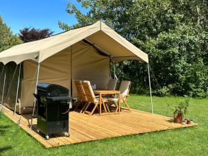 纳克斯考Langø Feriecenter - Outdoor Lodge的一个带桌椅和烧烤架的帐篷