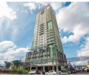 宿务Sunvida Tower Across SM City Cebu的一座高大的建筑,前面的人