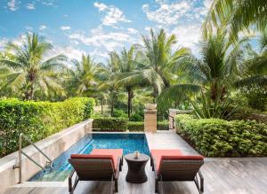 三亚三亚海棠湾JW万豪度假酒店(西班牙风情+迷你吧）的度假村旁的游泳池配有两把椅子和一张桌子