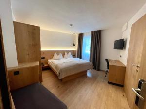 塞尔瓦迪加尔代纳山谷Hotel Des Alpes的配有一张床和一张书桌的酒店客房