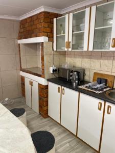吕德里茨The Oasis Accommodation的厨房配有白色橱柜和砖墙