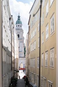 萨尔茨堡Altstadt-App. Domblick!的城市里一条以钟楼为背景的小巷