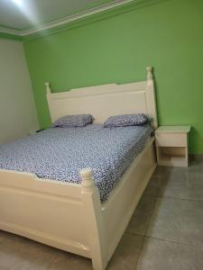 科纳克里Résidence Diakhaby的绿色墙壁的房间里一张白色的床