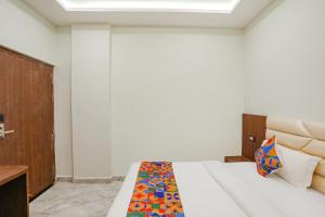 勒克瑙FabHotel DDS的卧室配有白色的床和色彩缤纷的毯子