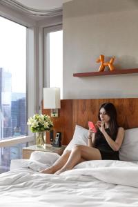 纽约纽约时代广场凯悦中心酒店的坐在床上看着手机的女人
