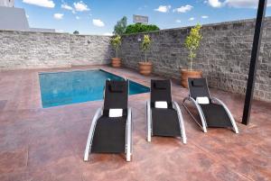 圣路易斯波托西La Quinta by Wyndham San Luis Potosi的后院设有两把椅子和一个游泳池