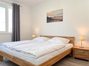 博尔滕哈根Weiße Villen Wohnung 20的卧室设有一张白色大床和一扇窗户。