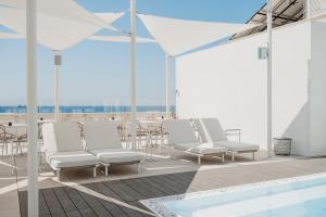 加利波利Biancodonda Lifestyle Hotel & SPA的一组白色椅子和一个屋顶游泳池