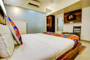 孟买FabHotel Kwality Inn的卧室配有一张白色大床和一把椅子