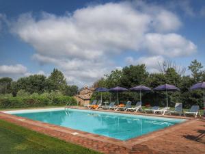 ProcenoCosy Farmhouse in Proceno with Swimming Pool的一个带椅子和遮阳伞的游泳池