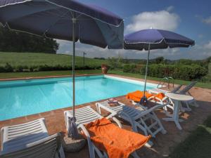 ProcenoCosy Farmhouse in Proceno with Swimming Pool的游泳池配有两把遮阳伞、两把椅子和一张桌子及椅子。