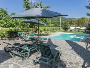 安布拉Authentic holiday home in Bucine with swimming pool的一组椅子和一把遮阳伞,位于游泳池旁