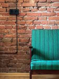库塔伊西Black Tomato Hostel Kutaisi的砖墙前的绿色椅子
