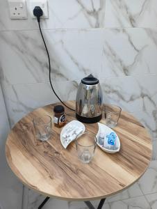 Al ‘Awālīابو عامر للشقق المفروشه的一张桌子,上面放着咖啡壶和玻璃杯