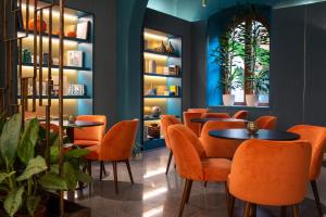 罗马Sentho Roma的一间设有橙色椅子和桌子的餐厅,种植了植物