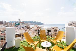 贝尼多姆Hotel Queens - Adults Only的阳台设有黄色椅子,享有海景。
