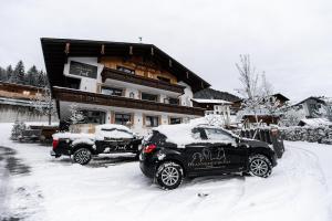 贝旺Mountainlodge Tirol Berwang的两辆停在大楼前雪地里的汽车