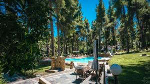 撒尼海滩Sani Cape Shared Pool Villas的公园里的一个游泳池,有椅子和树木