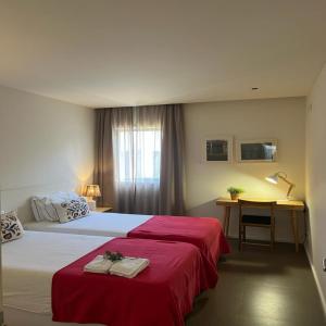 波尔图帕拉西奥波娜公寓式酒店的一间卧室配有两张带红色床单的床和一张书桌