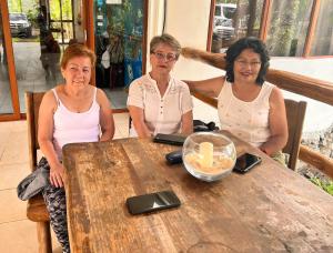 BellavistaNatura Gardens Galápagos的坐在木桌旁的三名妇女