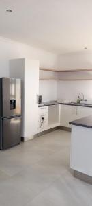 OkakararaEsteem Guesthouse的厨房设有白色的墙壁和不锈钢冰箱。