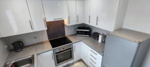 伦敦ExCel Exhibition Center Apartment的小厨房配有白色橱柜和电器