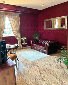 锡默拉特Garni Hotel Henn的客厅里设有真皮沙发,配有红色的墙壁