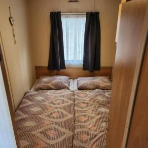 Mobilný domček na brehu Liptovskej Mary的一个小房间的一个床位,设有窗户