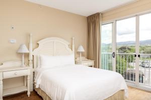 基洛纳Hotel Eldorado at Eldorado Resort的白色的卧室设有床和大窗户