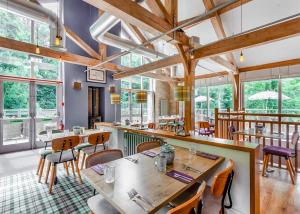巴斯巴斯工厂小屋度假酒店的餐厅设有木桌、椅子和窗户。