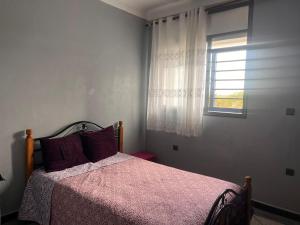 Abou Cristal House的一间卧室配有一张带粉色毯子的床和窗户。