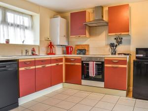 库姆马丁Roseus - Uk44706的厨房配有红色橱柜和黑色用具