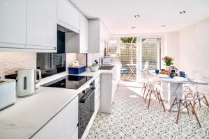 考斯Marina Bridge House Central Cowes的厨房配有白色橱柜和桌椅