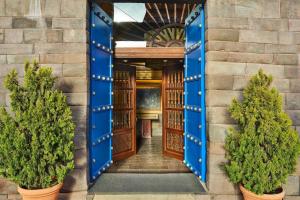 库斯科Palacio del Inka, a Luxury Collection Hotel, Cusco的拥有蓝色门和盆栽树木的建筑物入口