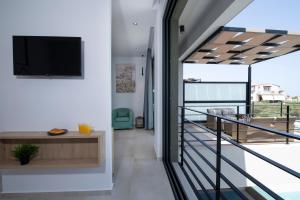 阿基阿婆斯托里Cretan Queen Residences的客房设有阳台,墙上配有电视。