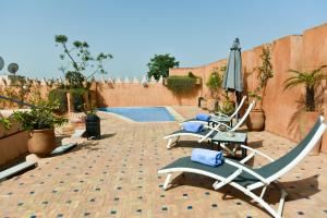 梅克内斯里亚德雅考特酒店的一个带椅子和遮阳伞的庭院和一个游泳池