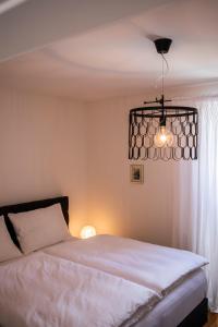 沃尔特湖畔韦尔登Seeapartment da Leopoldo I的卧室配有白色的床和吊灯。