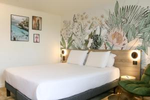 维特罗勒Kyriad Vitrolles Aéroport Marseille的卧室配有白色的床和花卉墙