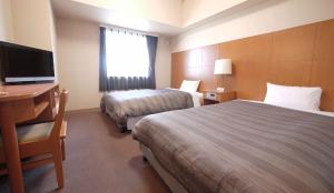 新庄新庄站前旅馆的酒店客房设有两张床、一张桌子和一台电视。