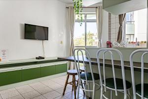 弗洛里亚诺波利斯Apto a 30 metros do mar em Canasvieiras CBE105的厨房配有绿色橱柜和带凳子的桌子