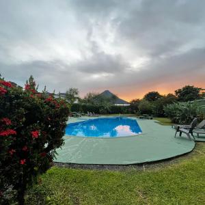 福尔图纳Hotel Villa Fortuna, Volcan Arenal, Costa Rica.的庭院内的游泳池,背景是日落