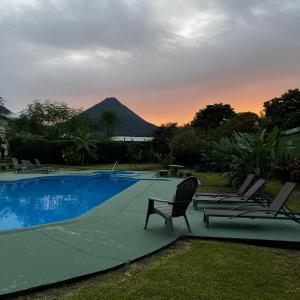 福尔图纳Hotel Villa Fortuna, Volcan Arenal, Costa Rica.的一个带椅子的游泳池,后方是一座山
