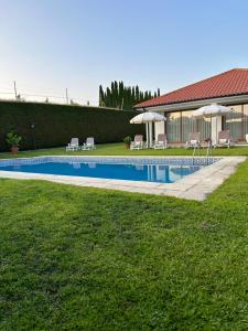 塞洛里库迪巴什图Villa Deluxe - Quinta do Outeirinho的房屋旁的游泳池配有椅子和遮阳伞