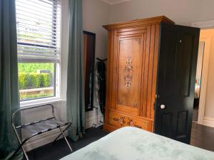 但尼丁Roslyn Business Studio - 2 bedroom的一间卧室配有木制橱柜和靠窗的椅子