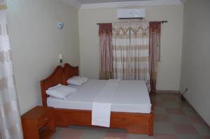 CococodjiMaison Verte a Cococodji的一间卧室配有一张带白色床单的床和一扇窗户。