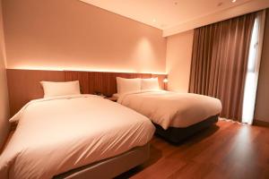 釜山Busan City Hotel的酒店客房设有两张床和窗户。